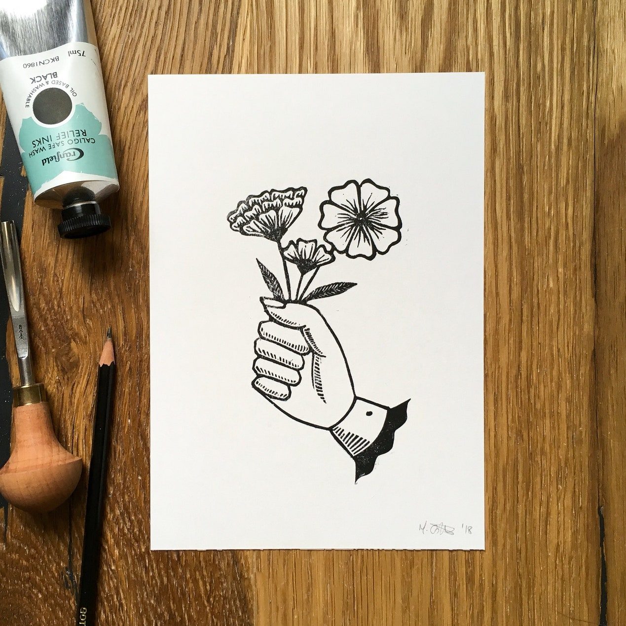 Linoprint of a hand clutching a small posey of flowers