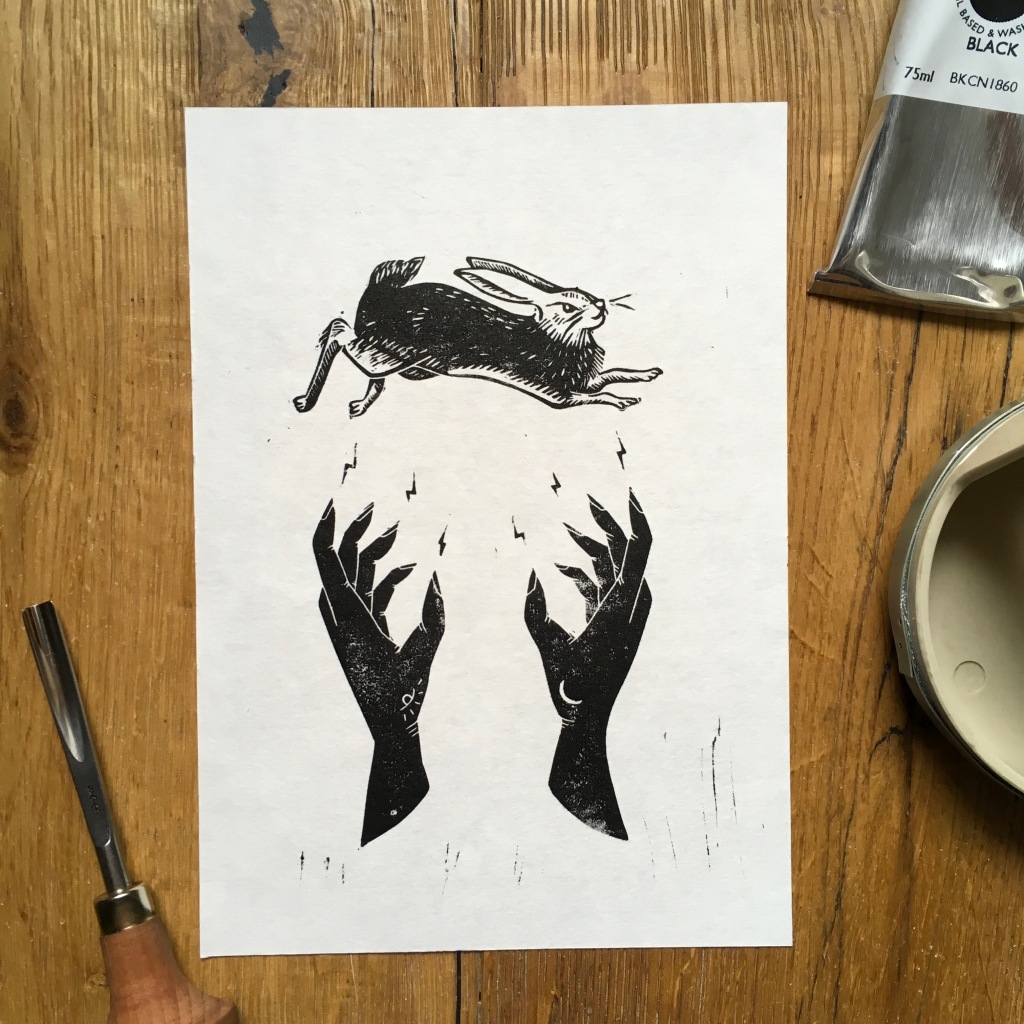 Linoprint of two hands conjuring a hare