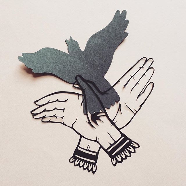 Papercut of two hands making a shadow bird
